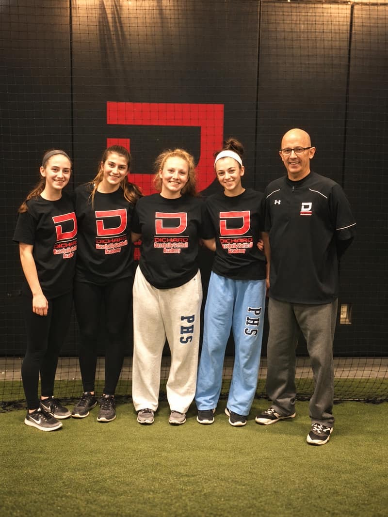 Lou DiChiaro with four softball players in front of the academy logo